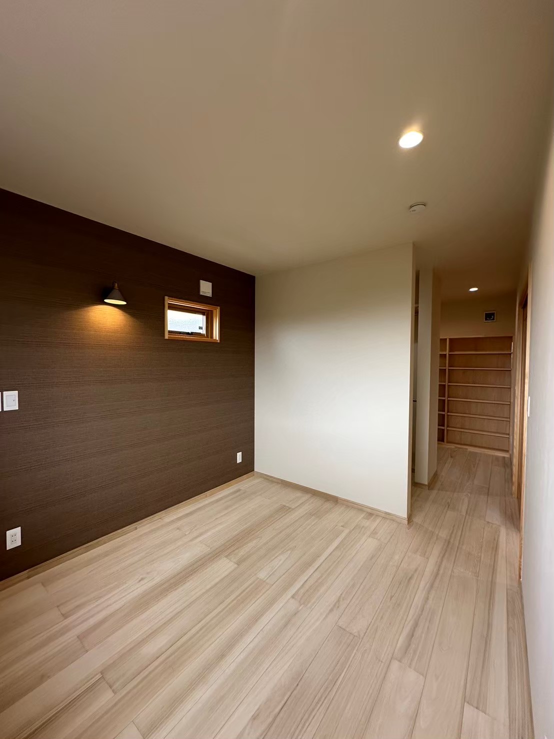 二階の洋室の奥には、書斎とたくさん収納できる本棚を作りました。無垢のフロアと茶色の壁紙がシックな洋室を演出。